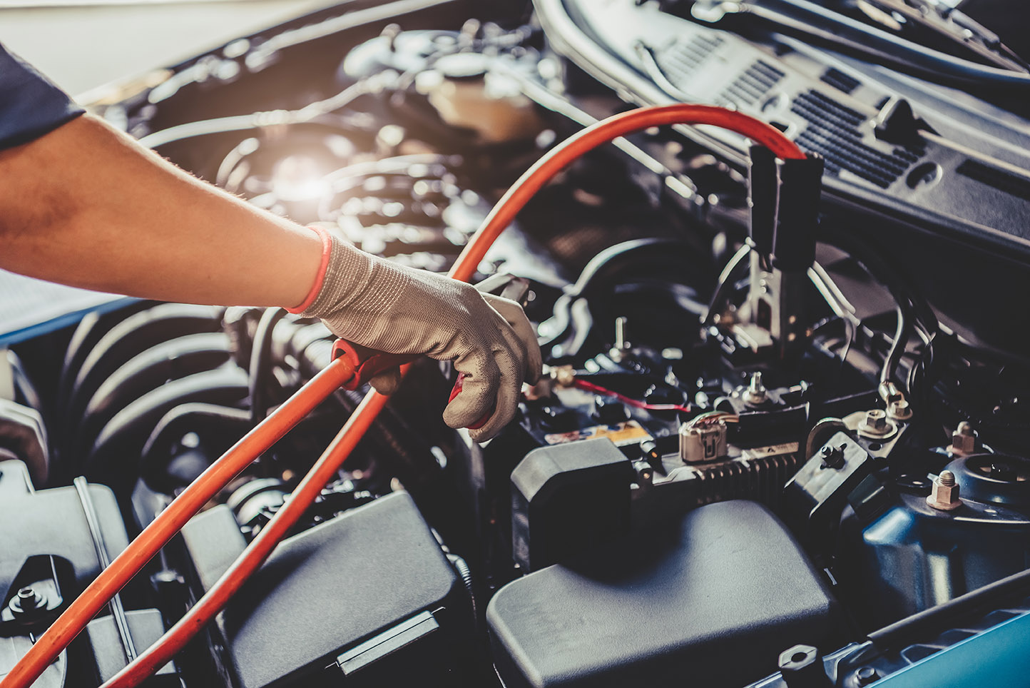 Car mechanic holding battery electricity trough cables jumper and checking to maintenance vehicle by customer claim order in auto repair shop garage. Repair service. People occupation and business job